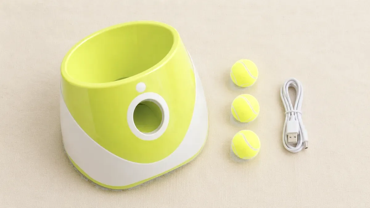 The launcher, its charging cable, the three balls and the manual laid flat on a cream background